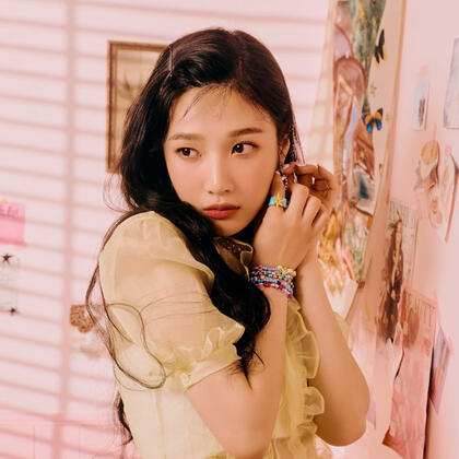 an orange Heng:garae photocard of Dk sitting on top of a car, leaning back slightly on his hands, and looking at the camera